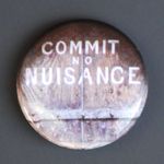 A small part of an old wood door on whicch is painted "Commit no nuisance".
